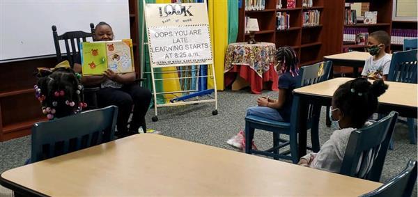 A volunteer reads to students at BISD.