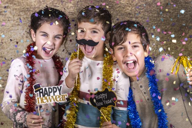 Kids celebrating new year with confetti and props.