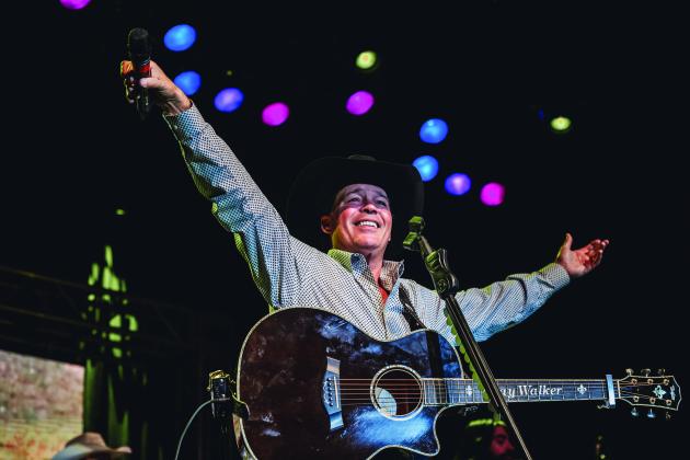 Clay Walker raises his arms at a live performance 