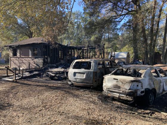 A wooden home located in the 1200 block on Diana Drive, along with a SUV and sedan vehicle, are destroyed by a Dec. 26 fire, south of Lumberton.  Photo by Dannie Oliveaux