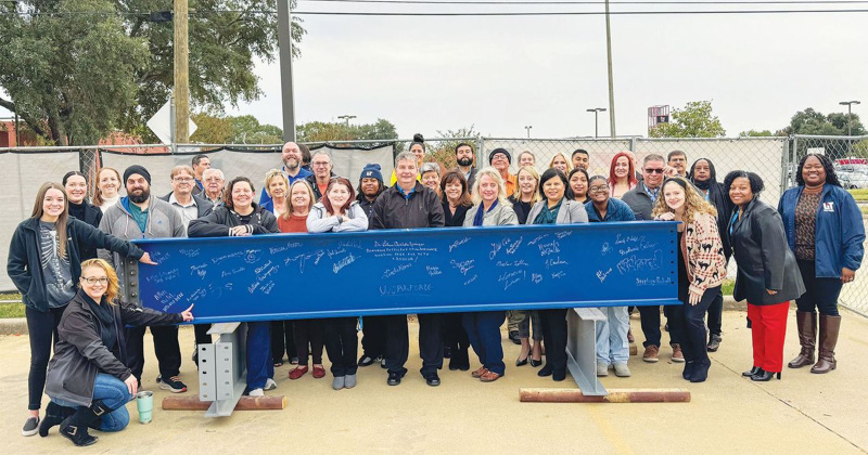 Faculty and staff sign and celebrate a construction milestone as steelwork closed on the Workforce and Allied Health Training Center.
